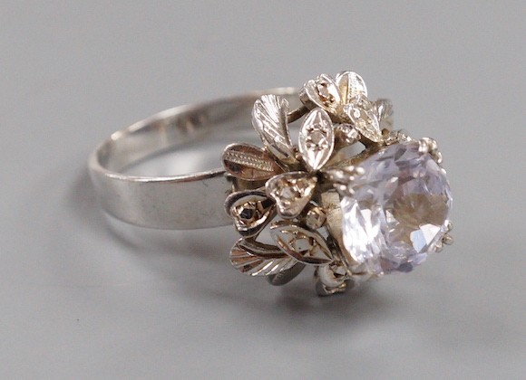 A modern white metal (tests as 18ct) and solitaire white sapphire set flower head ring, in a raised setting, size S/T, gross weight 8.1 grams.